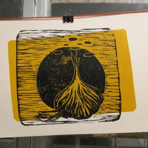Grabado artesanal de ajo en tinta negra sobre fondo amarillo