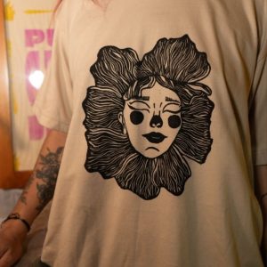 Camiseta beige con estampado artístico de rostro floral en color negro